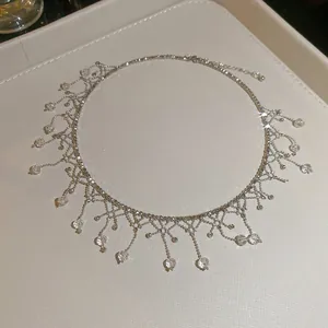Close-up of elegant crystal lace fringe choker necklace on a white textured tray.