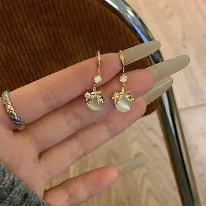 Elegant gold dangle earrings featuring cat-eye stones and shimmering rhinestone floral accents.