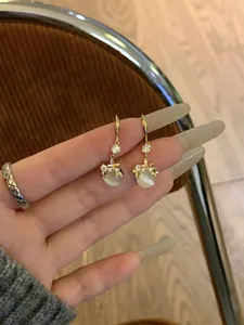 Detailed view of elegant gold-tone cat's eye dangle earrings with sparkling crystal accents