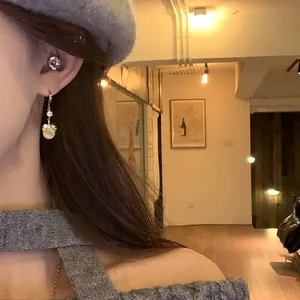 Close-up of elegant cat's eye stone pendant earrings with rhinestones worn on ear