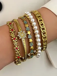 Macro view of retro bohemian gold bracelet stack featuring pearls and colorful rhinestones