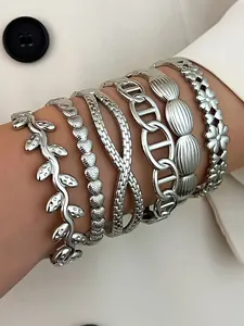 Close-up of six stacked silver stainless steel bracelets with various vintage patterns