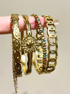 Detailed view of stacked vintage gold stainless steel bracelets with bohemian charms and crystals