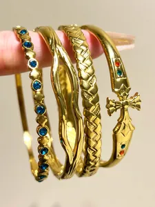 Close-up of four stackable gold stainless steel bangles with bohemian rhinestone details.