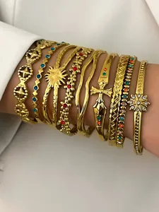 Close-up of stacked gold stainless steel bracelets with colorful rhinestones on arm