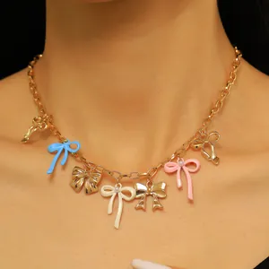 A close-up view of a sweet colorful enamel bow charm necklace worn by a female model.