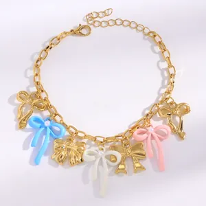 Detailed view of gold chain bracelet with colorful enamel bow pendants and pearls
