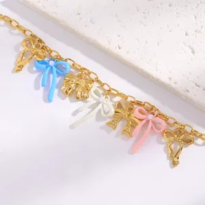 Macro detail view of colorful enamel bow charms on a delicate gold chain bracelet