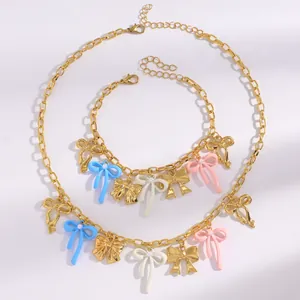 Golden necklace and bracelet set featuring colorful enamel bow pendants and pearls