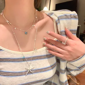 Detailed macro view of a double-layered necklace with starfish and pearl on model