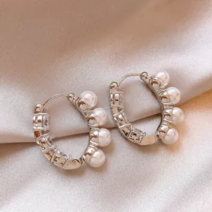 Detailed view of silver C-shaped hoop earrings with pearls and sparkling crystals.