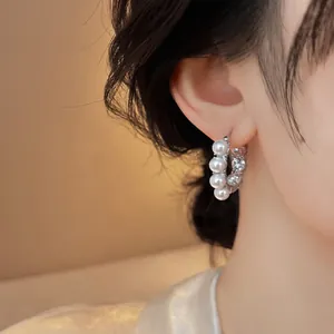 Close-up of elegant C-shaped French earrings featuring pearls and sparkling stones