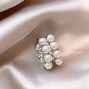 Detailed view of French C-shaped earrings with shiny pearls and sparkling stones