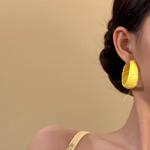 Vista detallada de elegantes pendientes de aro en C con encaje amarillo brillante en modelo
