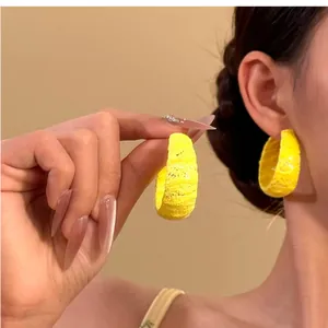 Detalle de los elegantes pendientes de aro de encaje amarillo en una modelo asiática