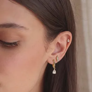 Gros plan de boucles d'oreilles en acier doré 18K avec des oxydes de zirconium poire