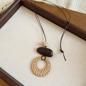 Detaillierte Ansicht eines gewebten Anhängers im Boho-Stil mit dunkelbrauner Perle und Kordel.