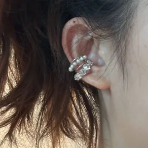Détail d'un earcuff à trois couches avec perles élégantes et zircons brillants