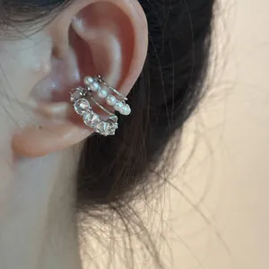 Gros plan détaillé d'un earcuff argenté multicouche orné de perles et de pierres de zircone