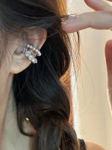Détail en gros plan d'un ear cuff multicouche en argent avec perles et pierres de zircon