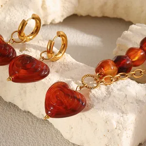 Detailed macro view of retro amber acrylic heart earrings with gold stainless steel hoops