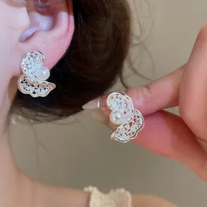 Macro view of sparkling zircon butterfly ear clips with elegant pearl inlay for women.