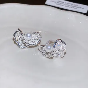 Detailed macro shot of sparkling zircon butterfly ear clips with central pearls.