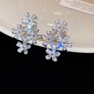 Close-up of elegant sparkling zircon flower clip-on earrings on a white ceramic plate