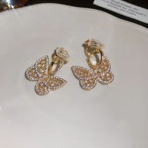 Close-up detail of golden butterfly clip-on earrings with sparkling pavé zircons