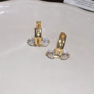 Detailed close-up showing the sparkling clear zircon stones on elegant gold hoop earrings