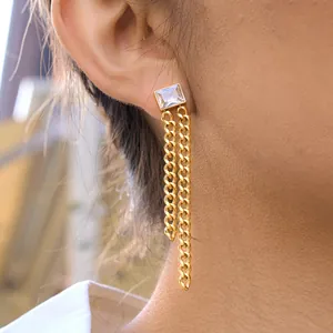 Close-up of golden titanium steel chain tassel earring with a square gemstone setting