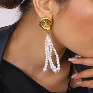 Close-up view of elegant gold spiral shell earrings with multi-strand white pearl tassels.