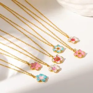 Dettaglio di collane con ciondolo a fiore in smalto colorato e catene d'oro su bianco