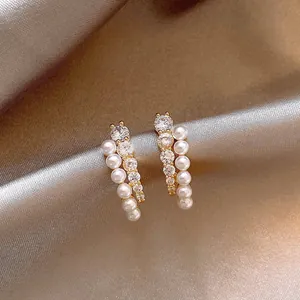 Vue détaillée de boucles d'oreilles de luxe avec zircons et perles sur fond de soie
