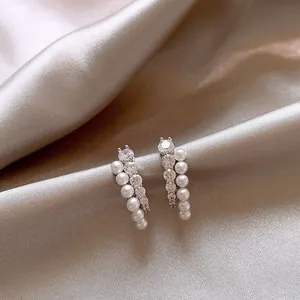 Gros plan d'élégantes boucles d'oreilles en zircon et perles sur un tissu en satin champagne