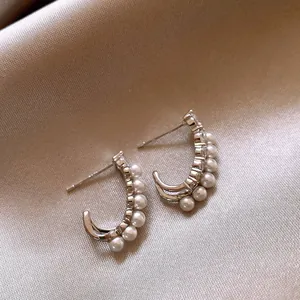 Gros plan sur des boucles d'oreilles en C avec perles et zircons