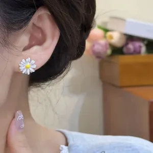 Close-up detail of a delicate white daisy flower stud earring worn on a female ear