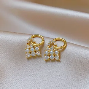Detailed macro view of French vintage pearl earrings with crystals on champagne satin.