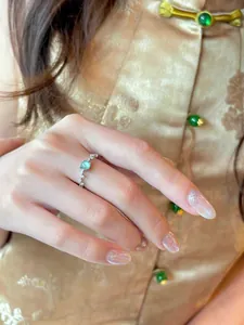 Primer plano de un anillo de circón brillante con una piedra verde claro en el dedo