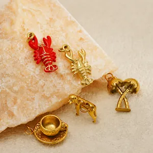 Detailed view of 18K gold plated stainless steel charms including lobster and palm tree