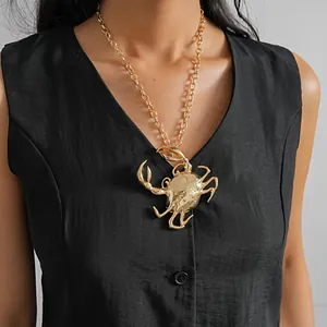Detalle de un llamativo colgante de cangrejo dorado metálico en una cadena gruesa