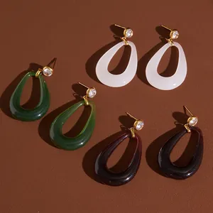 Detailed view of teardrop resin earrings in white, emerald green, and deep purple.