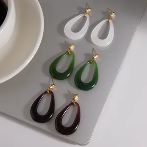Close-up detail of titanium steel resin teardrop earrings in white, green, and red