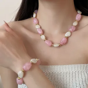 Nahaufnahme der Halskette und des Armbands mit rosa und weißen Acrylperlen-Details