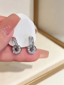 Detail of silver-colored hoop earrings with dangling sparkling pavé crystal discs.