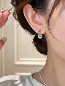 Detailed close-up of elegant silver disc hoop earrings with pavé stones on model's ear.
