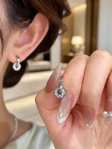 Close-up of small circular silver earrings with crystal pave setting