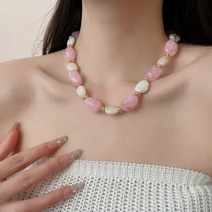 Nahaufnahme einer Retro-Acryl-Halskette mit rosa und weißen ovalen Perlen am Modell