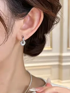 Close-up of elegant silver circular disc hoop earrings with crystal pavé on model's ear