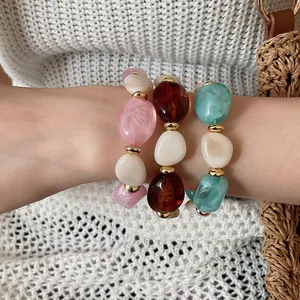Nahaufnahme von drei geometrischen Acryl-Armbändern an einem Handgelenk mit Strickpullover.